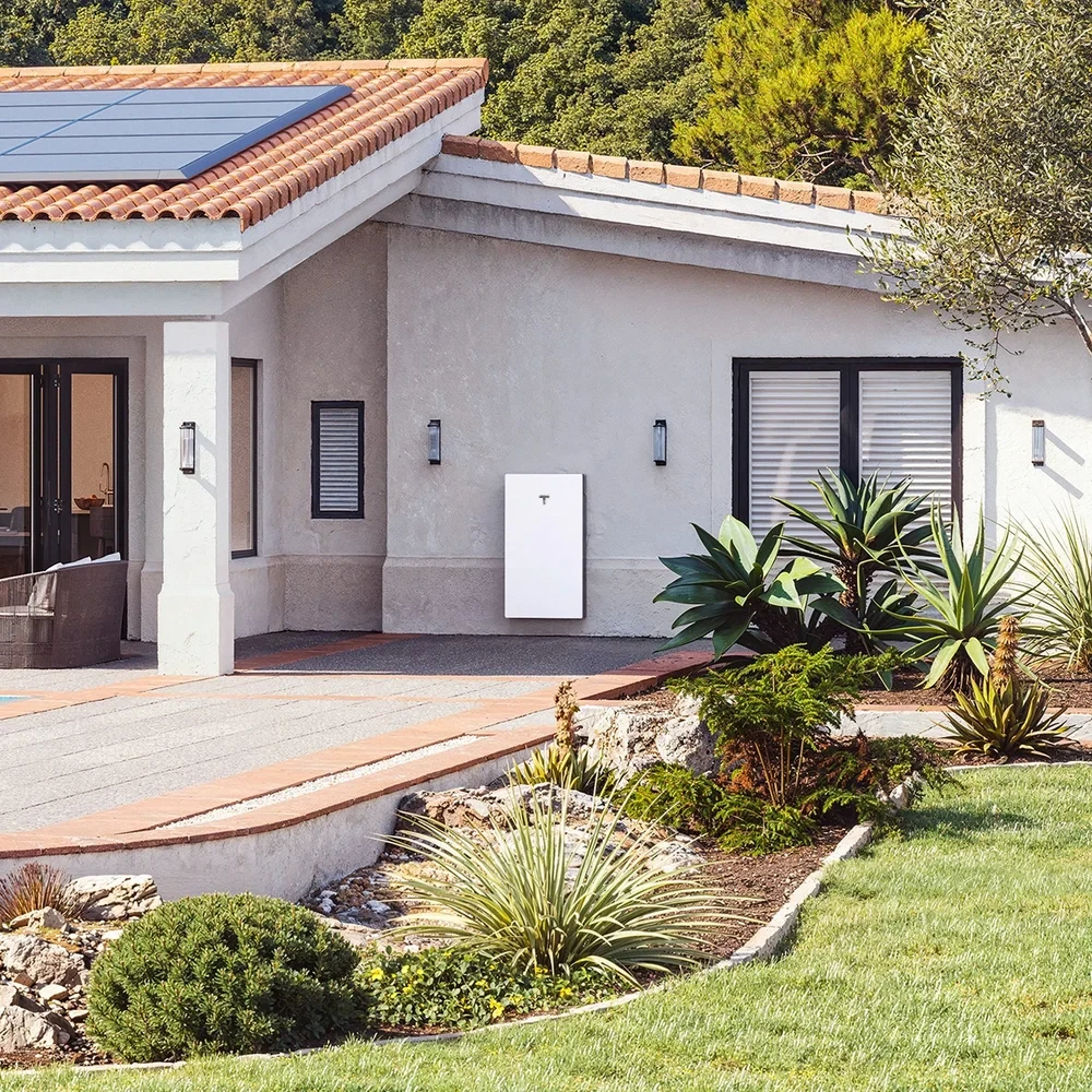 Moradia com painéis solares no telhado e uma Tesla Powerwall 3 na parede